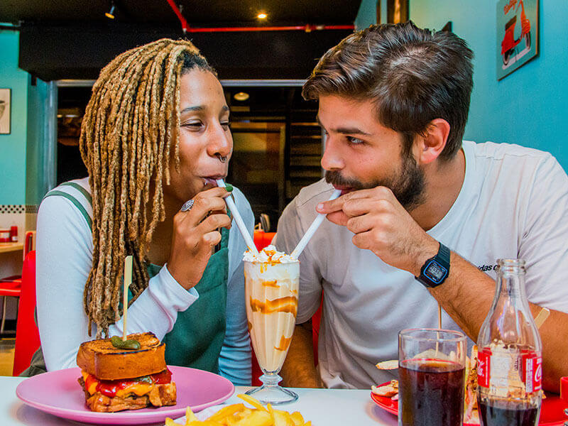 Duas pessoas dividindo um milkshake no diner da Jack The Burger